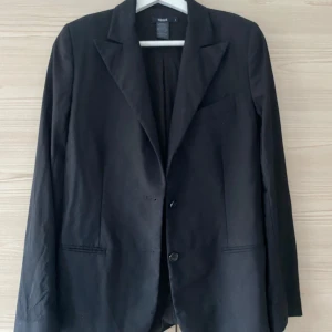 Svart kavaj Filippa K - Klassisk svart kavaj med två knappar framtill och smala slag. Perfekt att styla till både jeans och kostymbyxor, figursydd modell med fickdetaljer och helfodrad insida💗