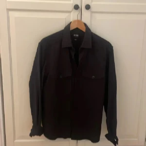 Svart overshirt från only sons  - Snygg svart overshirt från only sons  med långa ärmar och knappar framtill. Perfekt för lager-på-lager-stil. Passar bra till både casual och mer uppklädda tillfällen.