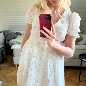 Vit klänning med puffärmar - Säljer en söt vit klänning med puffärmar och v-ringning. Klänningen har ett broderat mönster och knappar framtill. Perfekt för sommarens alla tillfällen! Helt oanvänd med lapp kvar!