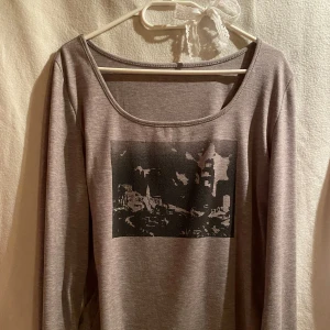 Grå långärmad topp med tryck - Säljer en grå långärmad topp med rund halsringning och svartvitt tryck framtill som föreställer en stadssilhuett. Mjuk och tunn bomullskänsla☺️