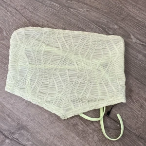 Ljusgrön tubtopp - Säljer en ljusgrön tubtopp med ett unikt, veckat mönster. 