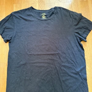 Svart t-shirt från Polo Ralph Lauren - Svart t-shirt från Polo Ralph Lauren med klassisk passform och rund hals. Tillverkad i 100% bomull och har den ikoniska röda broderade loggan nertill. Enkel och stilren design som funkar till allt.