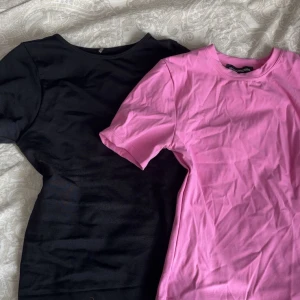 Svart och rosa compressive shirts - Två stilrena tränings t-shirts i svart och rosa från PrettyLittleThing. Formar kroppen fint och passar både till träning men även vardagskläder. Materialet känns mjukt och skönt mot huden. Storlek S men som sagt tight passform. Säljer gärna i par