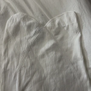 Vit ribbad tubtopp från Lindex - Säljer en snygg vit tubtopp från Lindex i storlek L. Toppen är ribbad med en bandeauformad överdel och har en stilren, enkel look. 