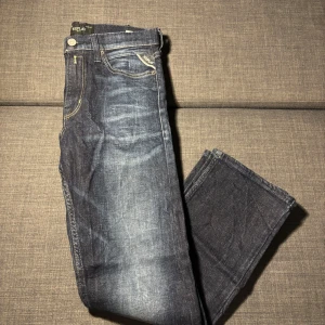 Blå Replay jeans Thad modell - Snygga blå jeans från Replay, modell. Jeansen har en rak passform och är tillverkade i slitstarkt bomullstyg. Jeansen ser lite slitna ut men använt endast 3 gånger.