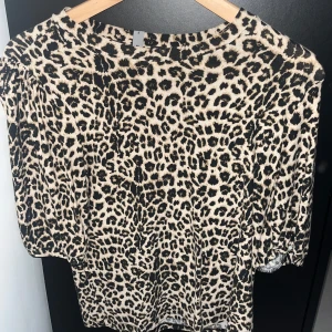 Leopardmönstrad tröja, XS - Snygg leopardmönstrad tröja i beige och svart. Tröjan har rund halsringning och puffiga korta ärmar som ger en trendig look. Perfekt för dig som vill sticka ut med ett djurmönster. Mjuk och skön känsla.