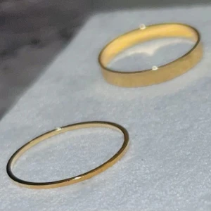 Set med fyra guldplaterade ringar - Fyra stilrena ringar i guld, två med smal design och två med bredare band. Kommer i en söt rosa organzapåse. Perfekta att mixa och matcha för en trendig look. Passar både som statement eller staplade tillsammans.