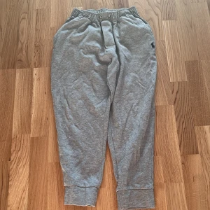 Grå mjukisbyxor från Ralph Lauren | 165 - Säljer ett par grå mjukisbyxor från Ralph Lauren med elastisk midja och mudd vid benslut. Byxorna har en liten broderad logga på vänster höft och är tillverkade i mjuk bomull för maximal komfort.