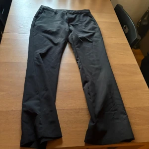 Svarta kostymbyxor från BikBok - Svarta kostymbyxor från BikBok i klassisk rak modell. Byxorna har hällor för bälte och stängs med dragkedja och knapp. Snyggt stilrena och passar perfekt till en dressad look. Materialet känns mjukt och följsamt. Storlek 40, men passar 36/38, små i storleken