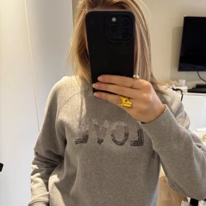 Grå sweatshirt med LOVE-tryck - Säljer en supersnygg grå sweatshirt från Zadig & Voltaire! Är använd väldigt sparsam och därför finns det inte heller några defekter. Någon enstaka sten på tröjan kan ha ramlat av men det är absolut inget man märker när man kollar på tröjan!! Säljer pågrund av att jag ej använder den speciellt mycket💗