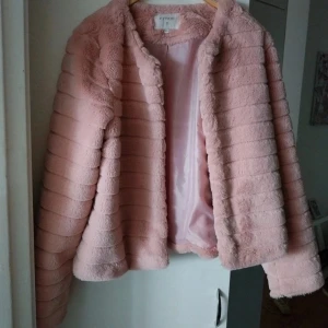 Ljusrosa pälsjacka från Cream - Supermjuk ljusrosa pälsjacka från Cream i storlek 40. Jackan har horisontella sömmar som ger en cool struktur och är helfodrad med glansigt tyg. Perfekt för dig som vill ha en mysig och trendig look under kyliga dagar.