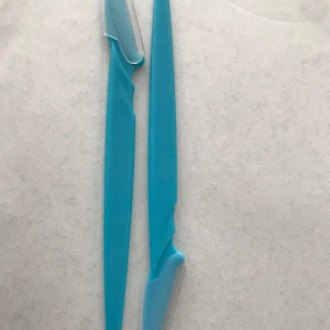 2st Blå ögonbrynstrimmers  - Två blå ögonbrynstrimmers med smalt handtag och skydd för bladet. Perfekta för att forma och trimma ögonbryn eller ta bort små ansiktshår. Tillverkade i plast med metallblad för enkel och smidig användning.