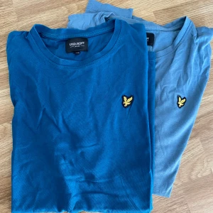 2-pack Lyle & Scott t-shirts blå - Två stilrena t-shirts från Lyle & Scott i olika blå nyanser. Båda har klassisk rund hals, korta ärmar och den ikoniska gula fågel-loggan broderad på bröstet. 