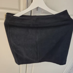 Svart mockakjol från Esmara - Snygg svart kortkjol från Esmara by Heidi Klum i mjuk mocka-look. Kjolen har en enkel och stilren design med dragkedja i sidan. Perfekt att matcha med en stickad tröja eller t-shirt för en cool vibe.