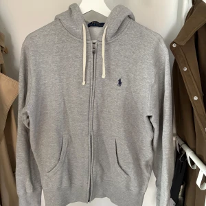 Grå hoodie från Polo Ralph Lauren - Snygg grå hoodie från Polo Ralph. Skön och stilren till vardagliga autfits, den är i grymt skick knappt använd, pris diskuteras vid snabb affär 🤝