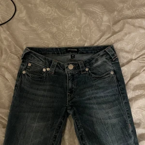 True Religion jeans i mörkblå denim - Säljer ett par snygga True Religion jeans i mörkblå tvätt med rosa detaljer! Använda ca 3 ggr men är som helt nya i skicket. Köpare står för ev frakt ❣️❣️
