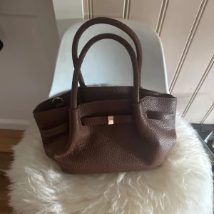 Väska - Gullig brun handväska med gulddetalj!  Aldrig använd!! Märket är okänt då jag köpte den av en kompis helt ny!🌸