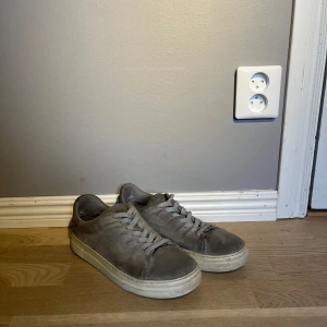 Grå mockasneakers från Selected Homme - Tjena, säljer nu mina Snygga grå sneakers i mocka från Selected Homme med klassisk rund tå och platt vit sula. Mockan har fortfarande skit bra! Användes för ett tag sedan och sen dess bara stått och dammat, köpte för 1400 och är inte så använda. Priset är inte heller hugget i sten så är bara att höra av sig 