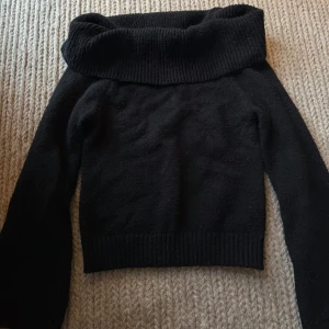 Svart polotröja med bred krage - Snygg svart off shoulder tröja. Tröjan är långärmad och har ribbade muddar vid ärmslut och nederkant. Perfekt för kyliga dagar och enkel att matcha med olika outfits. Är osäker på vart den kommer ifrån. 
