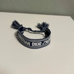 Armband från Dior - Ett snyggt stickat armband från Dior. Armbandet är justerbart så den passar alla. Den är i nyskick och har inga defekter. Ställ frågor vid funderingar