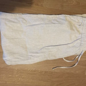 Beiga linnebyxor med snörning - Säljer ett par ljusbeiga linnebyxor med avslappnad passform och snörning i midjan. Byxorna har raka ben och är perfekta för varma dagar. Materialet är svalt och luftigt linne, vilket ger en chill och stilren vibe.
