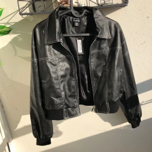 Svart skinnjacka - Snygg svart skinnjacka från Boohoo med vita kontrastsömmar och dragkedja framtill. Jackan har en klassisk krage, ribbade muddar och en lite oversized passform. Jag råkade köpa två likadana så därför är det två likadana annonser i min profil.