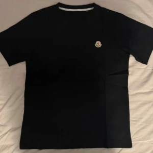 Moncler T-shirt  - Snygg stilren svart oanvänd Moncler t-shirt med klassisk passform och rund hals. Liten Moncler-logga på bröstet ger en stilren touch. Perfekt till alla tillfällen jeans eller shorts för en clean klass look, pris kan diskuteras vid snabb affär