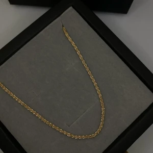 Tunt guldhalsband med kedjelänk - Snyggt och stilrent halsband i guldton med tunn kedja och täta länkar. Perfekt för dig som gillar minimalistiska smycken med en touch av lyx. 