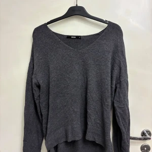 Mörkgrå v-ringad tröja från Bik Bok - Mysig mörkgrå tröja från Bik Bok med v-ringad hals och lång ärm. Tröjan har en loose passform och är tillverkad i ett mjukt stickat material. (Behöver strykas). 