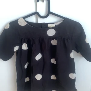 Svart prickig blus från Pomp de Lux - Svart blus från Pomp de Lux med stora vita prickar. Modellen har korta hår och ganska så tajta ärmar, och rynkor vid bysten. Andvänd fåtal ggr, säljer då den inte passar mig🖤 står att det är barnstorlek men skulle nog säga att den också passar XS