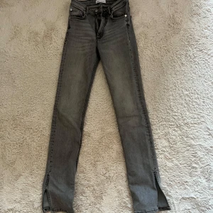 Gråa jeans - Gråa jeans från Zara som har använts fåtal gånger. Jeansen är högmidjade och har en slits nertill. Storlek 34 men passar mig som har långa ben och är 168 cm. Säljer då jeansen inte kommer till användning längre!