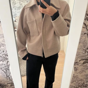 Beige kappa från NA-KD - Säljer min beiga vårjacka/kappa som passar perfekt till våren! Finns både knappar och dragkedja att stänga jackan med, även en ficka på ena sidan🥰 