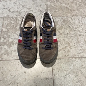 Moncler skor  - Snygga grå sneakers från Moncler modell Monaco. Skorna är i bra skick utseendemässigt men på insidan i vänstra skon är det slitningar i hälen. Det kostar 300 att laga hos en skräddare ifall man skulle vilja göra det. Allt og ingår storlek 43. Skriv privat för fler bilder och vid minsta fundering. 