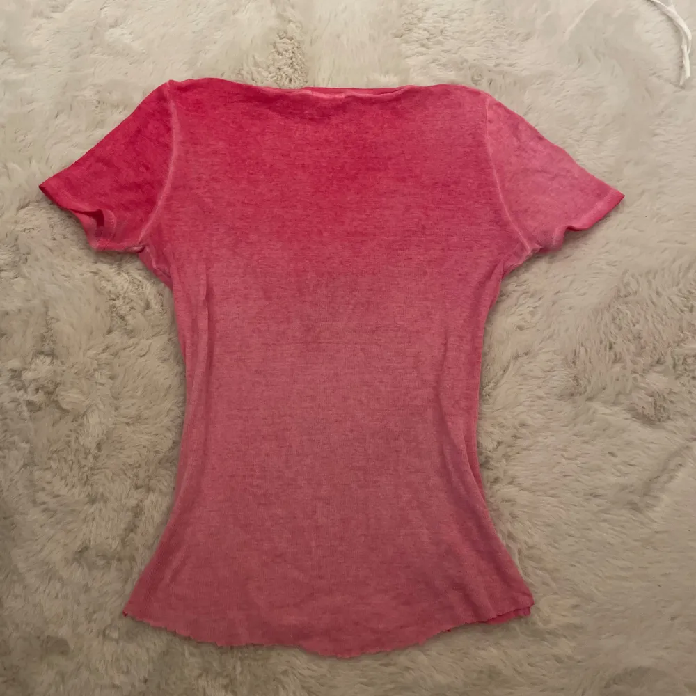 Hej! Säljer denna super söta rosa u-ringade t-shirten med knappar på. Toppen är tunn och luftig och perfekt till en varmare sommar/vår dag. Jag har klippt längst ner i den då den var väldigt lång innan. Den är lik toppen på dom två 2 sista bilderna (lånade bilder) men den är inte precis likadan!💓Toppen har inga defekter förutom ett pyttelitet hål vid knapparna (bild 3). Om ni skulle ha några frågor är det bara att höra av er!💕💕. T-paidat.