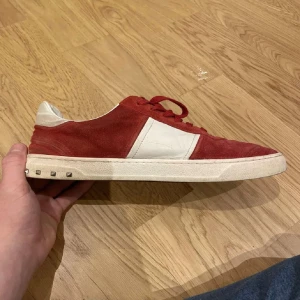 Röda Valentino flycrew - Snygga röda sneakers i mocka från Valentino med vita detaljer och ikoniska nitar på hälen. Alla nitar finns kvar och box ingår. Mitt pris endast 2399