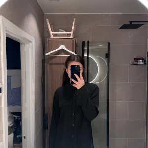 Svart skjorta från stories - Svart långärmad skjorta med knappar och knyt i ryggen. 