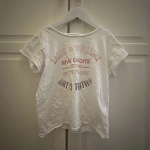 Vit t-shirt från Zadig & Voltaire - Säljer en vit t-shirt från Zadig & Voltaire med tryck i rosa  och svart. Texten 'Rive Droite' och 'Art is Truth. Inga fläckar eller hål bra skick!