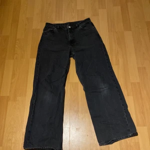 Svarta jeansbyxor - Säljer ett par svarta jeansbyxor med en klassisk design. Byxorna har en rak passform och är tillverkade i ett slitstarkt material. Perfekta för en stilren look.
