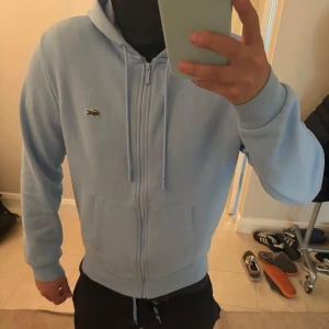 Lacoste zip hoodie - Säljer en stilren ljusblå hoodie från Lacoste | storlek M men sitter som S | helt ny och nytt skick typ | nypris 1700kr | köp nu🙂