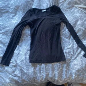 Svart långärmad topp från Vila - Säljer en svart långärmad topp från Vila. Toppen har en enkel design med rund halsringning, ganska tunn men ej genomskinlig. Den har använts mycket, därav har den lite småtrådar och är lite smått urtvättad. Men passar perfekt att ha antingen för sig själv eller under något annat 