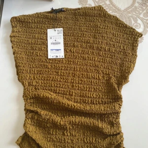 Zara topp - Säljer en gul ribbad topp med en unik textur. Toppen har en lös passform och är perfekt för en avslappnad stil. Den är tillverkad i ett mjukt och bekvämt material.