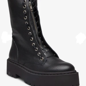 Steve Madden - Snygga svarta boots i skinn med både snörning och dragkedja för enkel på- och avtagning. De har en robust platåsula som ger extra höjd och stil. Perfekta för en edgy look.
