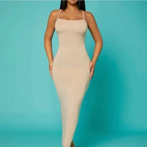 Beige långklänning med smala axelband - Elegant beige långklänning med smala axelband och öppen rygg. Klänningen har en tight passform som framhäver figuren och är perfekt för en stilren look. Säljer för 45kr, pris kan alltid diskuteras hos mig!❤️