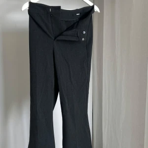 Svarta kostymbyxor från BikBok - Snygga svarta kostymbyxor från BikBok i storlek 36. Byxorna har en klassisk design med knappar och dragkedja framtill. 