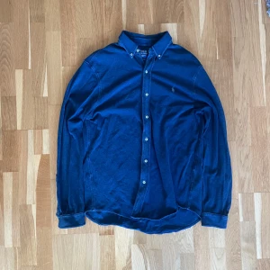 Blå Ralph Lauren skjorta storlek L - En fet Ralph Lauren skjorta perfekt till sommaren, inga defekter i storlek L, priset är inte satt så skicka ett prisförslag så kan vi lösa nått!