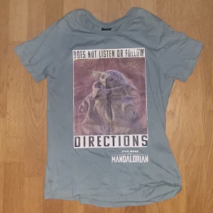 Grön Star Wars T-shirt med Mandalorian-tryck - Säljer en grå T-shirt med ett coolt Mandalorian-tryck på framsidan. Perfekt för alla Star Wars-fans! 👽Tröjan är knappt använd alls, så skicket är nästintill perfekt. Den är i 158/164, men kan även passa liten S. Tveka inte att höra av dig om du har någon fråga!