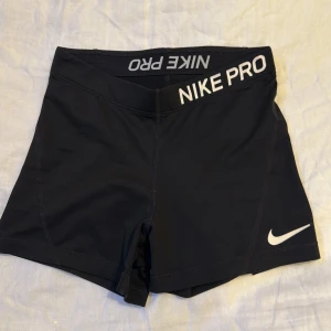 Svarta träningsshorts från Nike - Säljer ett par svarta Nike Pro träningsshorts med vit logga och text på linningen. Dom är knappt använda och därmed säljer jag dom 💕