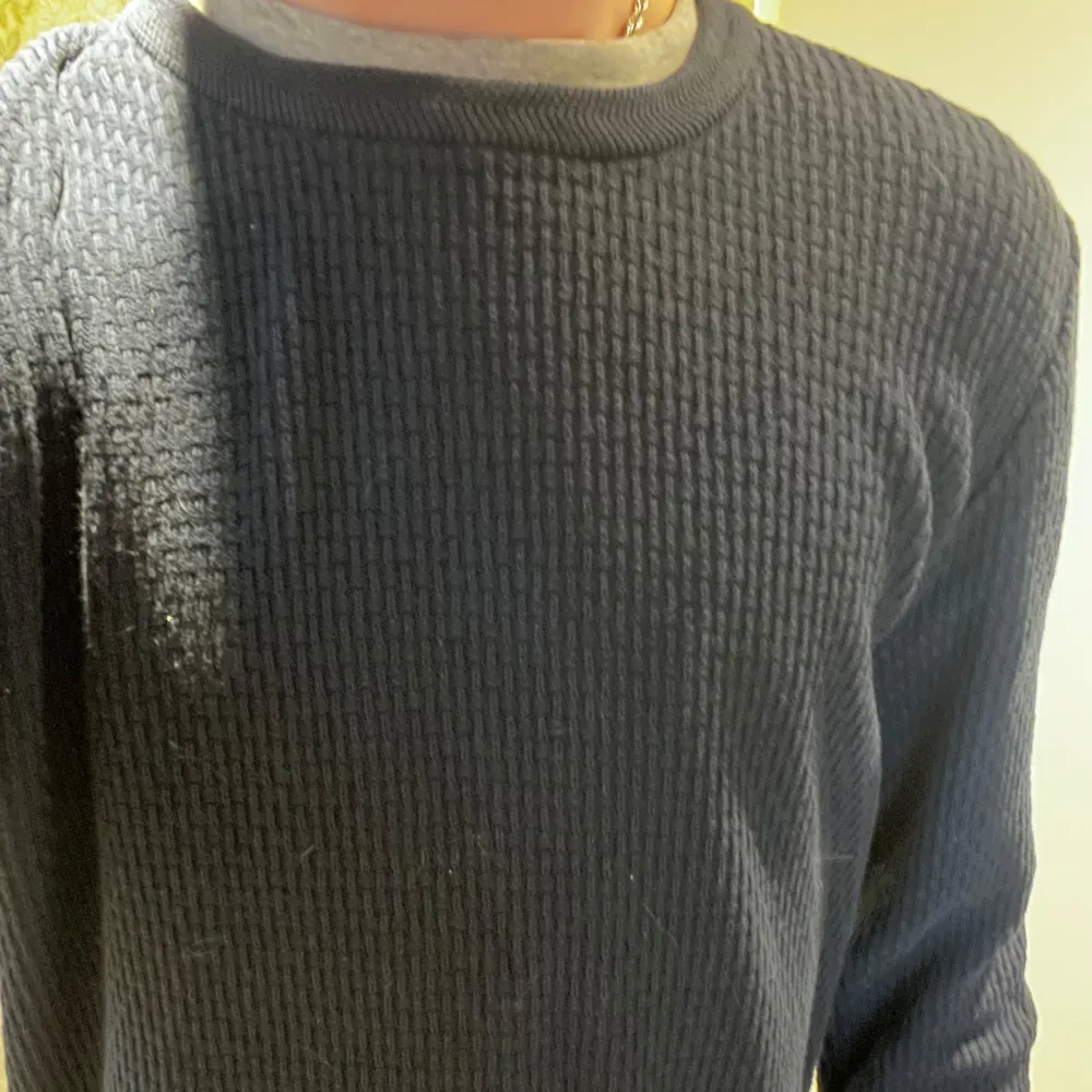 Säljer en stilren mörkblå stickad tröja med rund hals. Perfekt för kyliga dagar och passar till det mesta i garderoben. Tröjan har långa ärmar och en bekväm passform.. Neuletakit & Villapaidat.