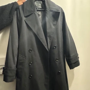 Svart trenchcoat från Mango - Trenchcoat från Mango i storlek XS köpt i butik 17/4-2025. Köpt för 1199 kr, inte använd. Jag kan inte returnera då jag av misstag bort prislappen. Kvitto finns. Pris kan diskuteras!