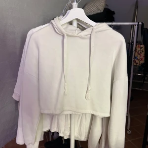 Vit hoodie från Gina Tricot - Säljer en vit hoodie från Gina Tricot. Den har en croppad design med långa ärmar och en klassisk huva med dragsko. Perfekt för en avslappnad stil.